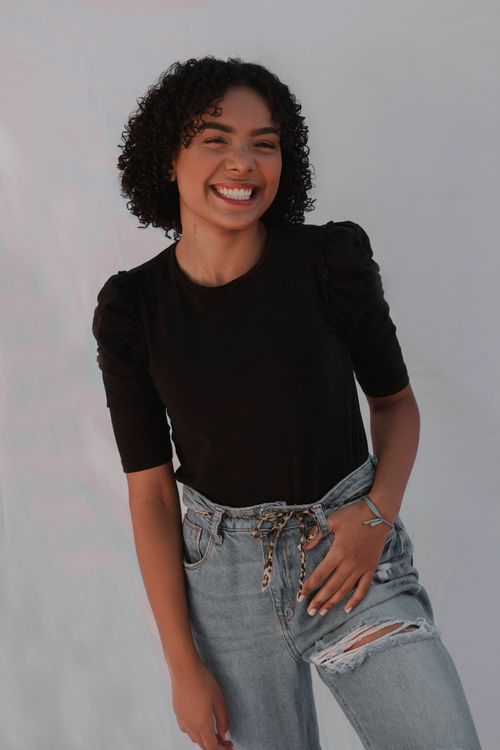 Free Portrait of a cheerful woman wearing a black blouse and jeans, captured in a studio setting. Stock Photo