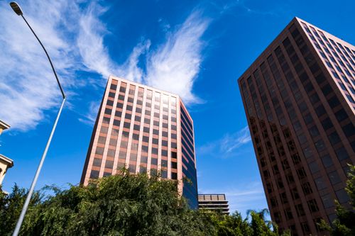 Free Two modern skyscrapers reaching into a vibrant blue sky, captured from a low-angle perspective. Stock Photo