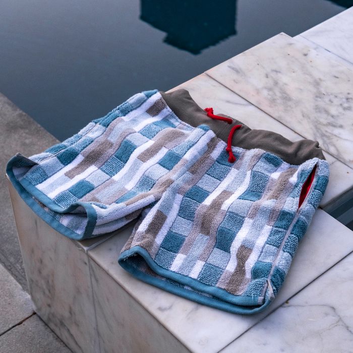 Folded checked swim shorts on stone — photo by Malcolm Garret on Pexels
