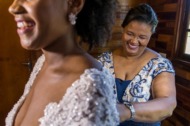 A Mother Zipping The Wedding Gown Of Her Daughter