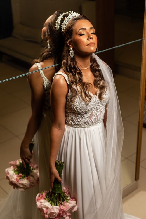 Free Bride in white wedding gown holding bouquet, standing near mirror. Stock Photo