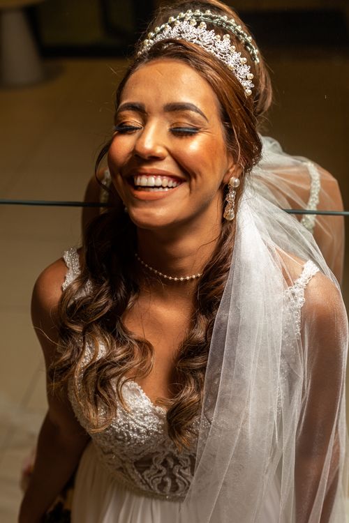 Free Elegant bride with a radiant smile and tiara reflecting in a mirror. Capturing wedding joy indoors. Stock Photo
