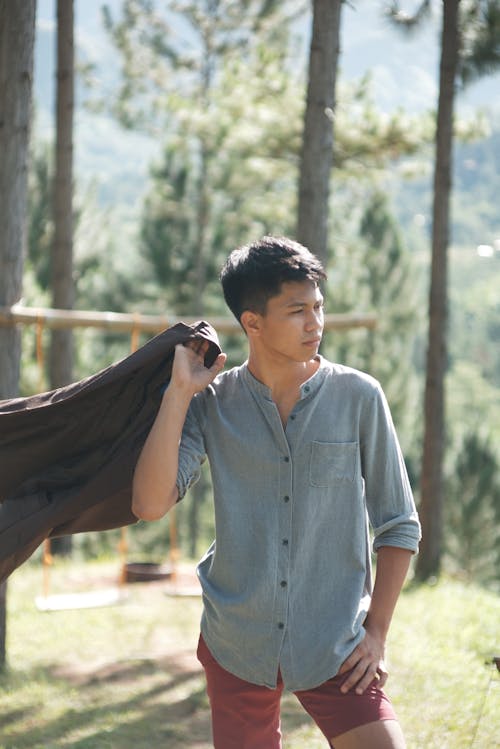 A Man in a Blue Top and Shorts Posing with a Jacket at His Back