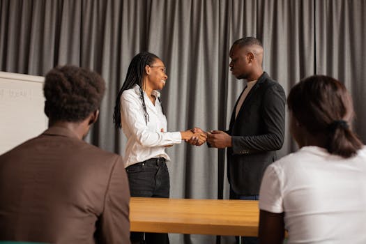 Two professionals shaking hands during a meeting, symbolizing agreement and partnership.