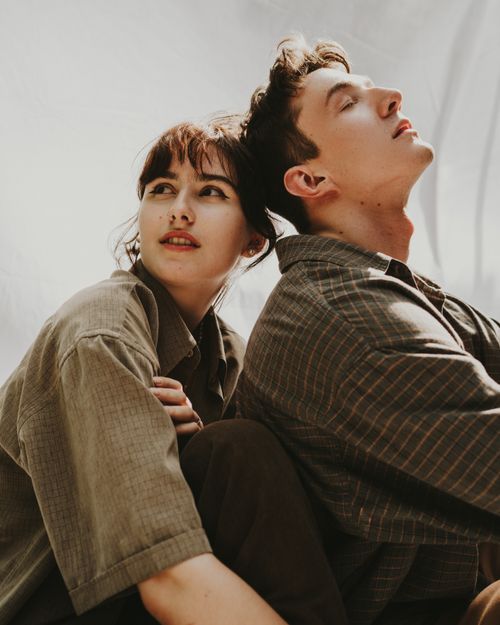 Free A candid moment of a young couple leaning against each other, enjoying a sunny day. Stock Photo