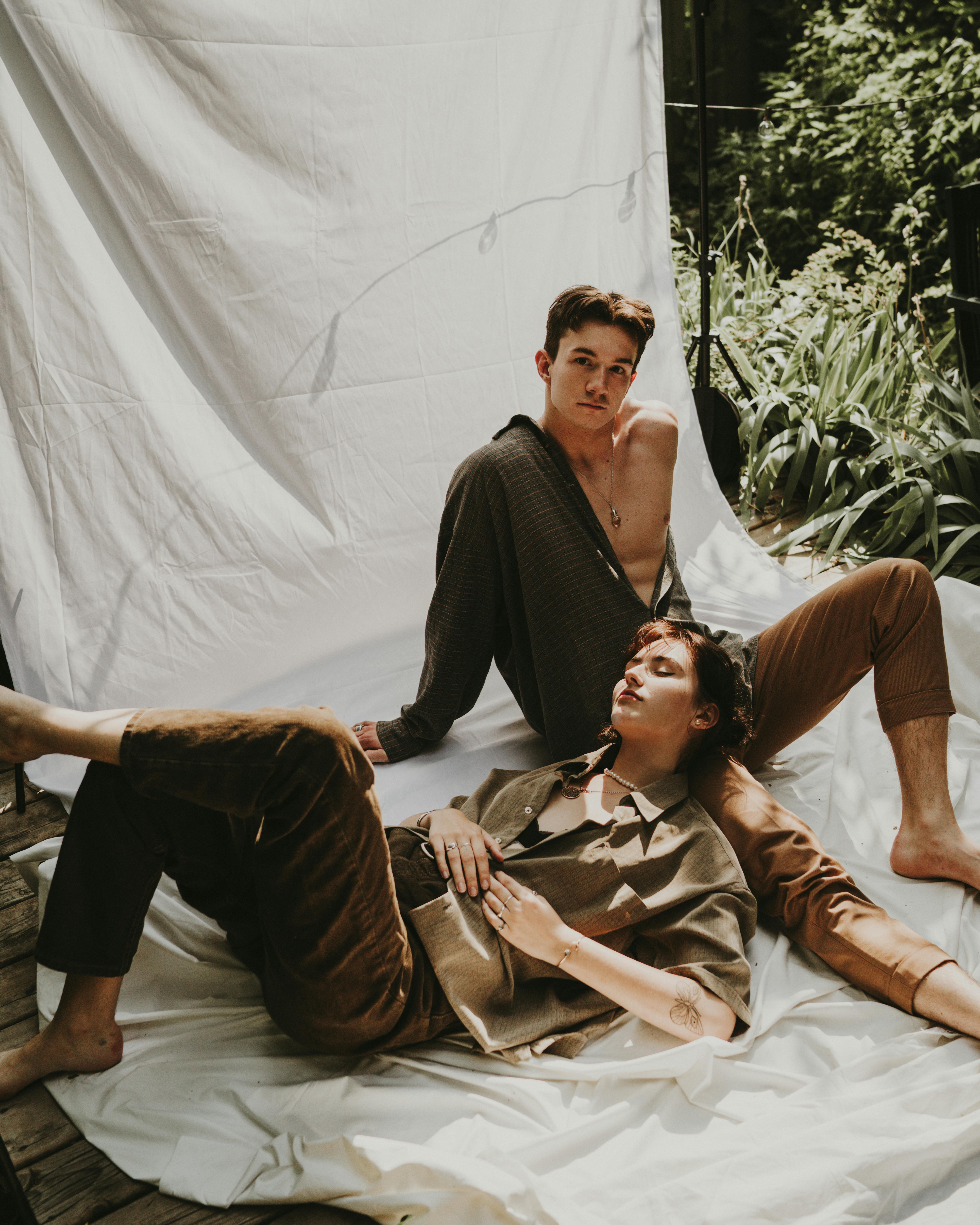 A couple lounging comfortably under the sun with a lush green background.