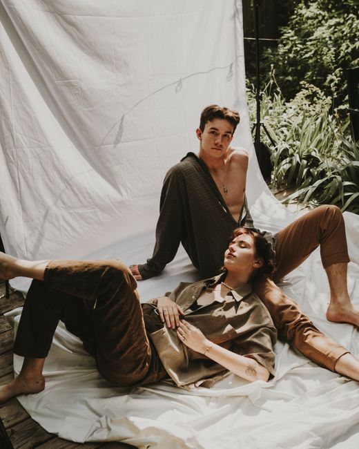 A couple lounging comfortably under the sun with a lush green background.