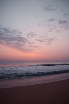 Peaceful beach scene with gentle waves under a pastel-hued sunset sky.