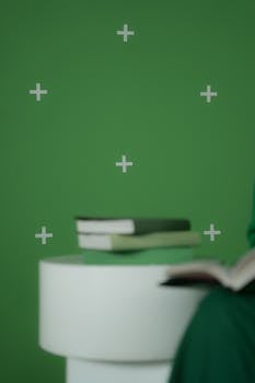 Books placed on a round table against a green chroma key background, ideal for digital media projects.