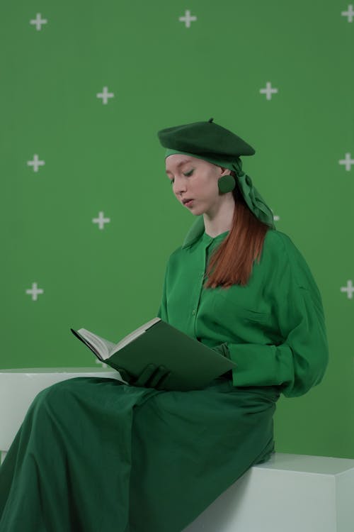 Red Haired Woman in Green Clothing Reading Book in Studio