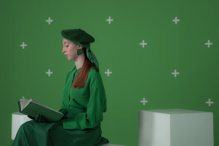 A Woman In A Green Outfit Reading A Book