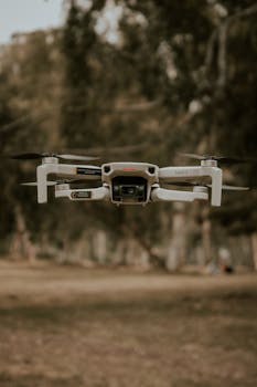 Close-up of a drone hovering outdoors in a forest setting.