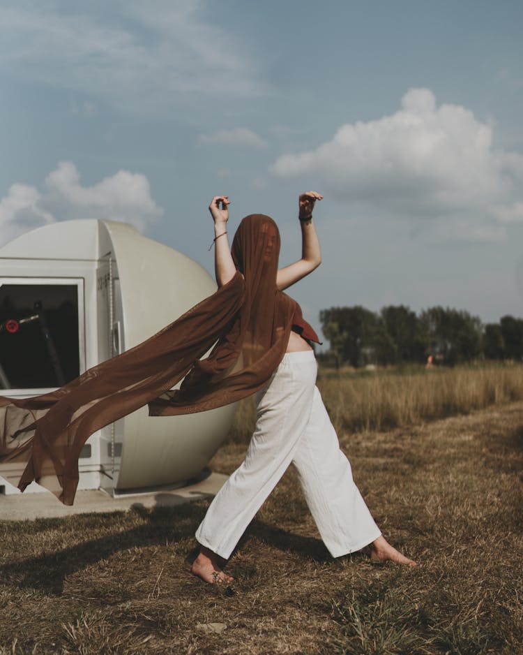 
A Woman With A Scarf On Her Head Walking On A Field