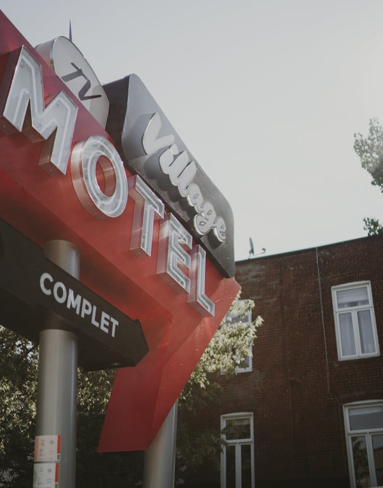 A Red Signage Of Motel Beside A Brown Building