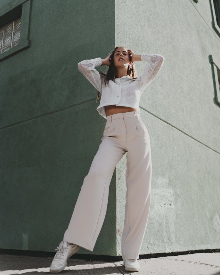 A Woman Wearing A White Long Sleeved Shirt And Wide Leg Pants