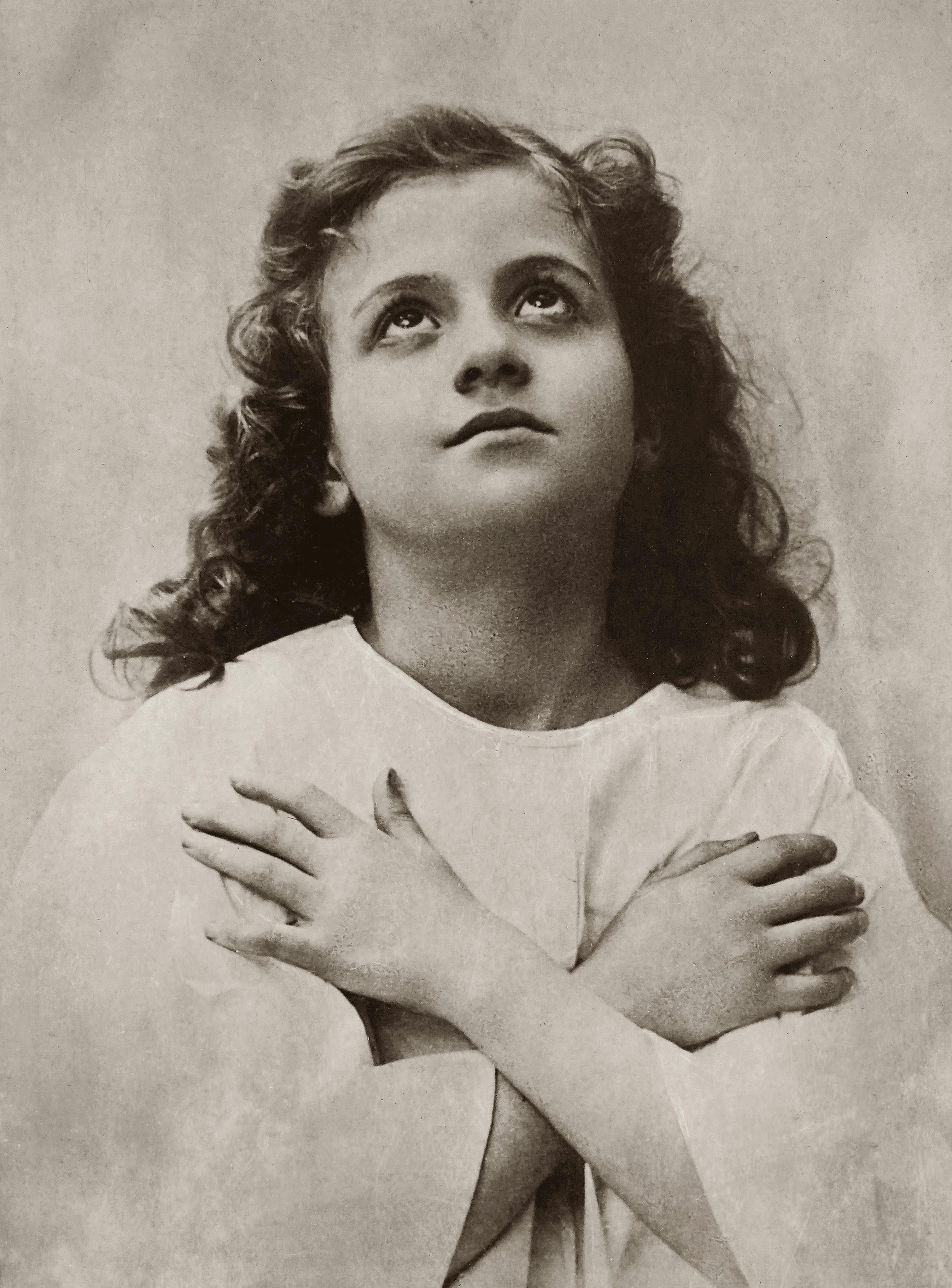 A sepia-toned portrait of a young girl looking upwards, evoking a sense of nostalgia.