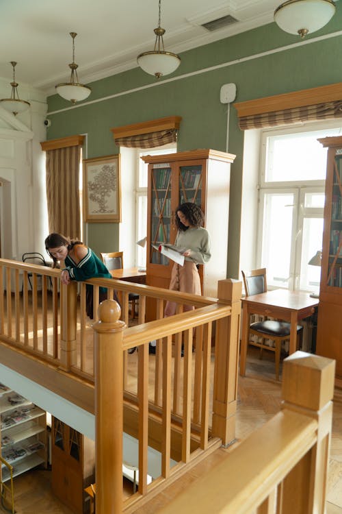 Free Young Women Standing on the Second Floor of a Library  Stock Photo