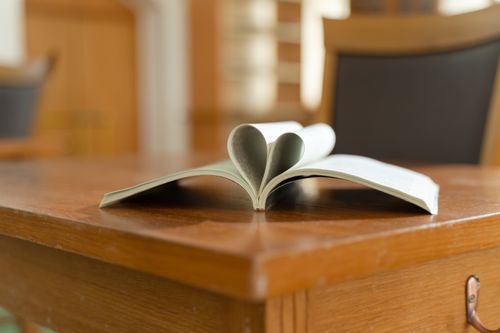 Free Open book with heart-shaped pages on a wooden table in a cozy room. Stock Photo