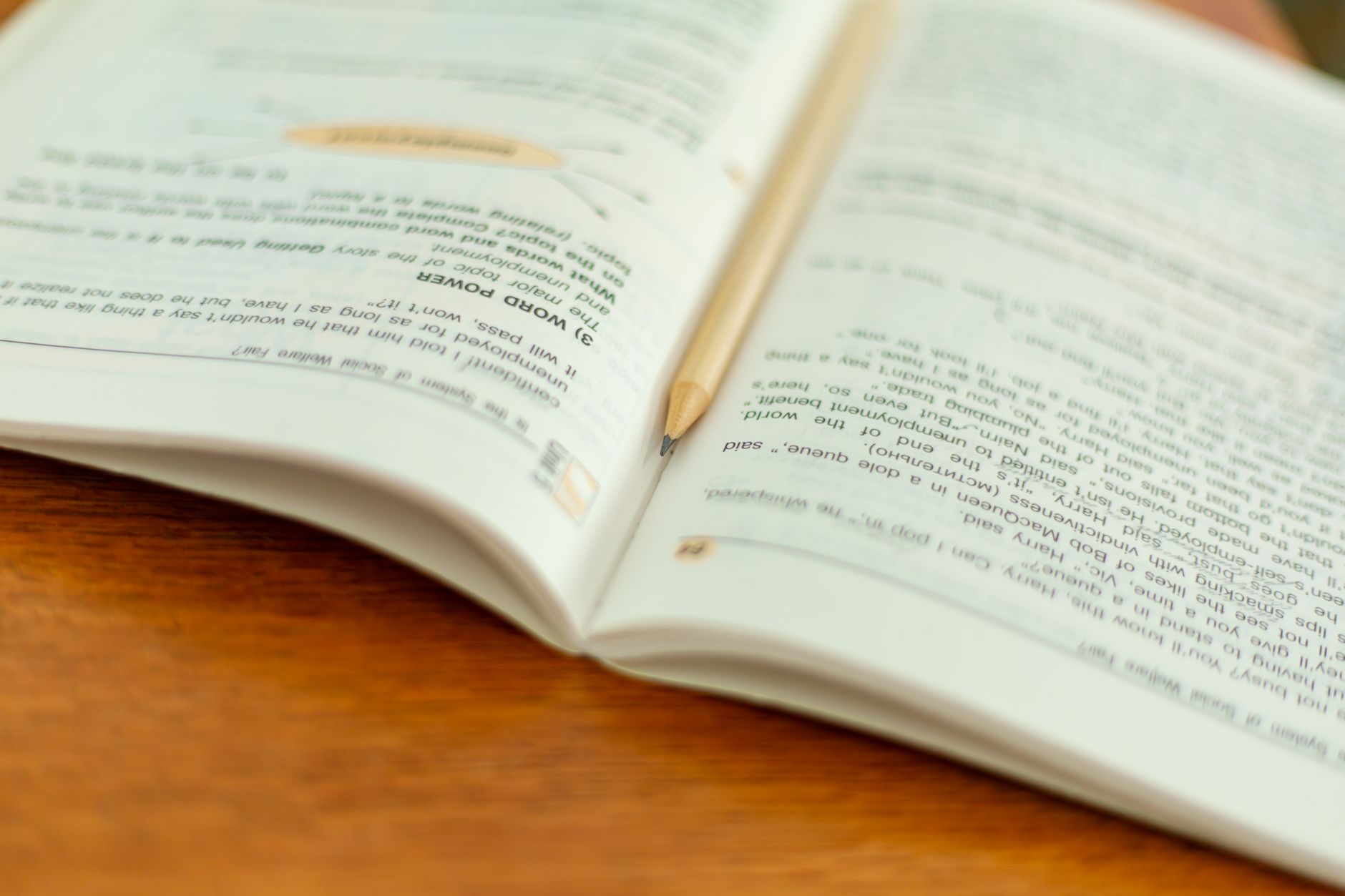 An open book with a pencil on a wooden table, perfect for educational themes.