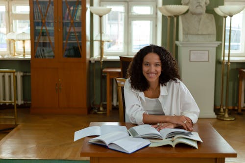 Woman Sitting on Chair Studying While Smiling 
