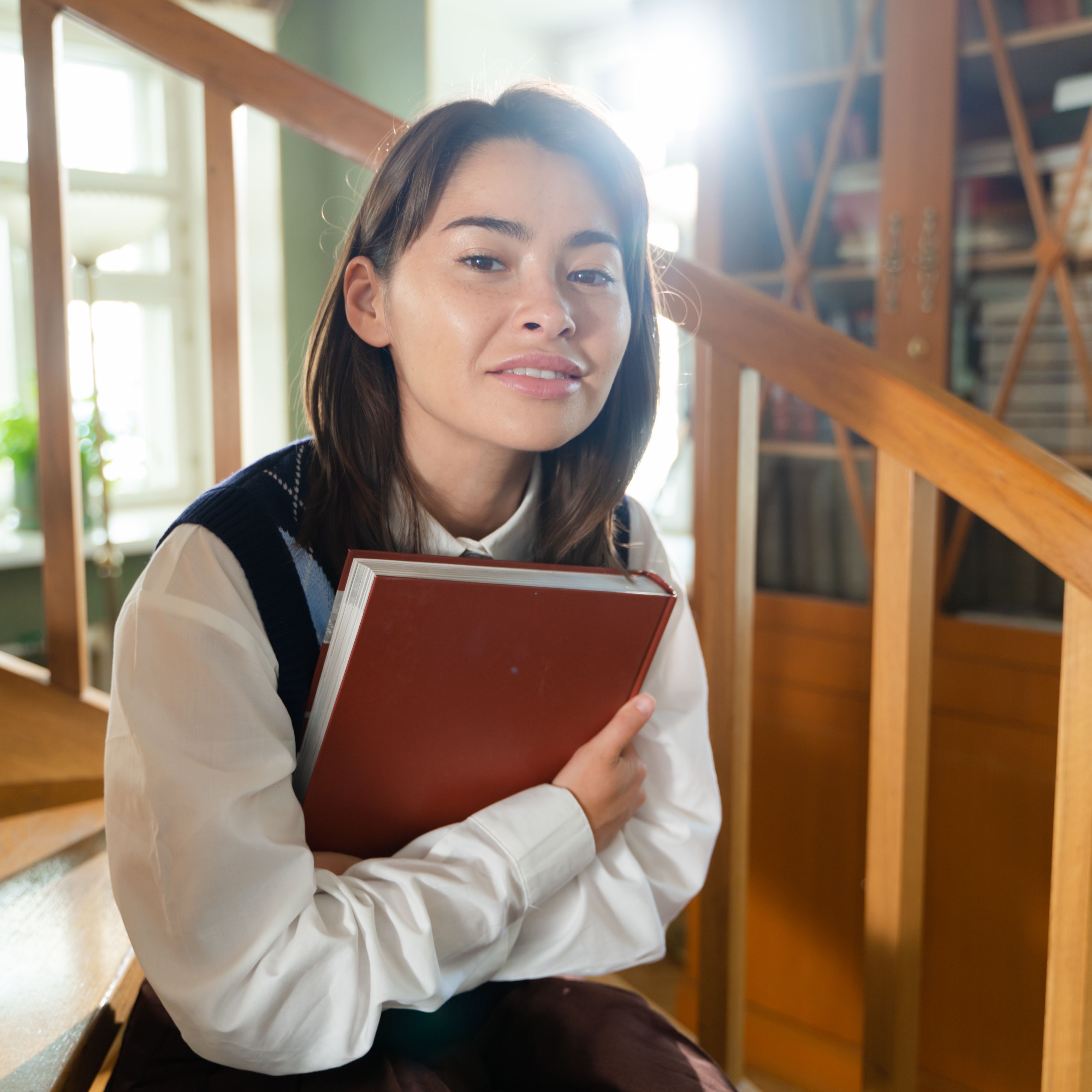 Woman in White Long Sleeve Shirt Holding Brown Book