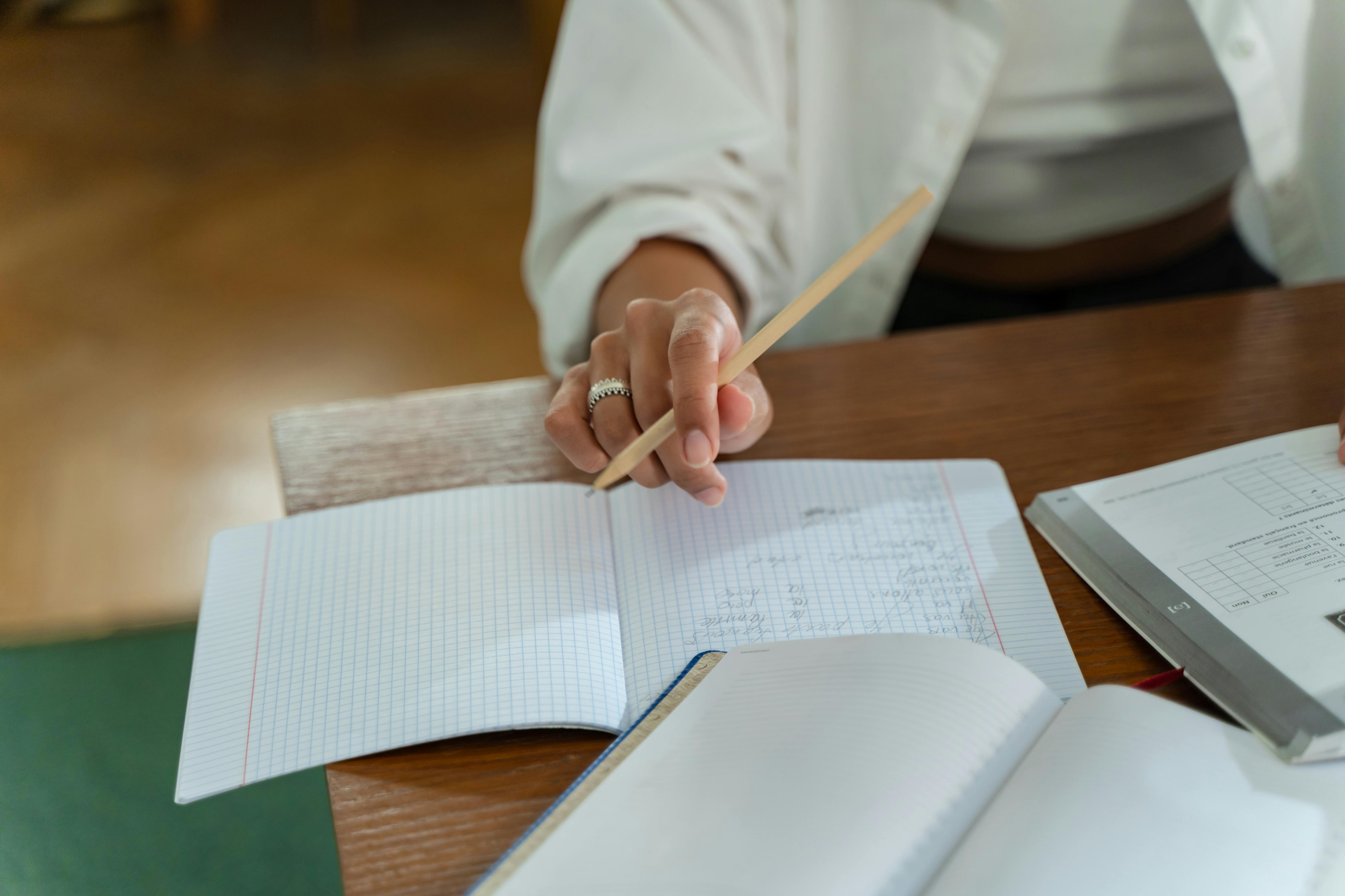 person sitting on wooden table holding a pencil