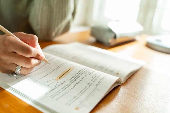Student answering questions in an open textbook and notebook