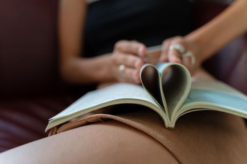 Free Close-up of a person's hands holding a book with pages folded into a heart shape. Stock Photo
