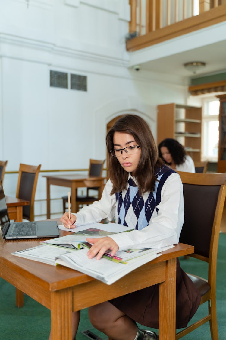 A Woman In White Long Sleeves Studying In The Library