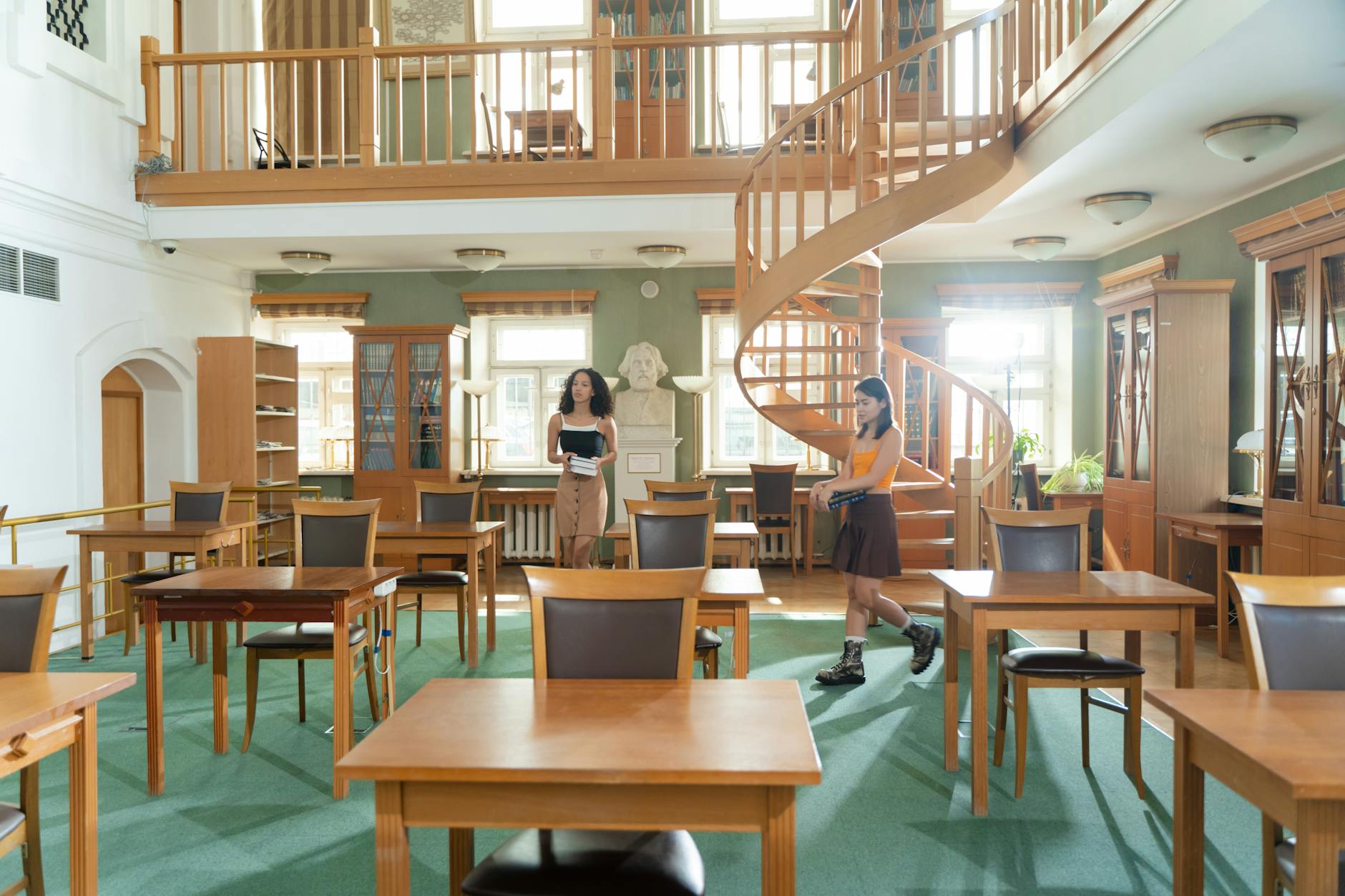 Spacious university library featuring wooden interior and spiral staircase, ideal for learning.