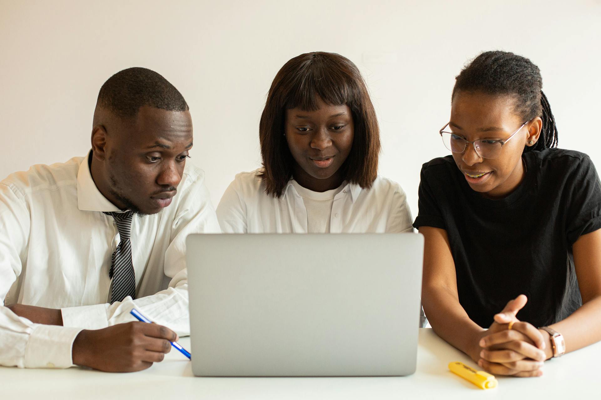 Three professionals working together on a project using a laptop in an office setting.