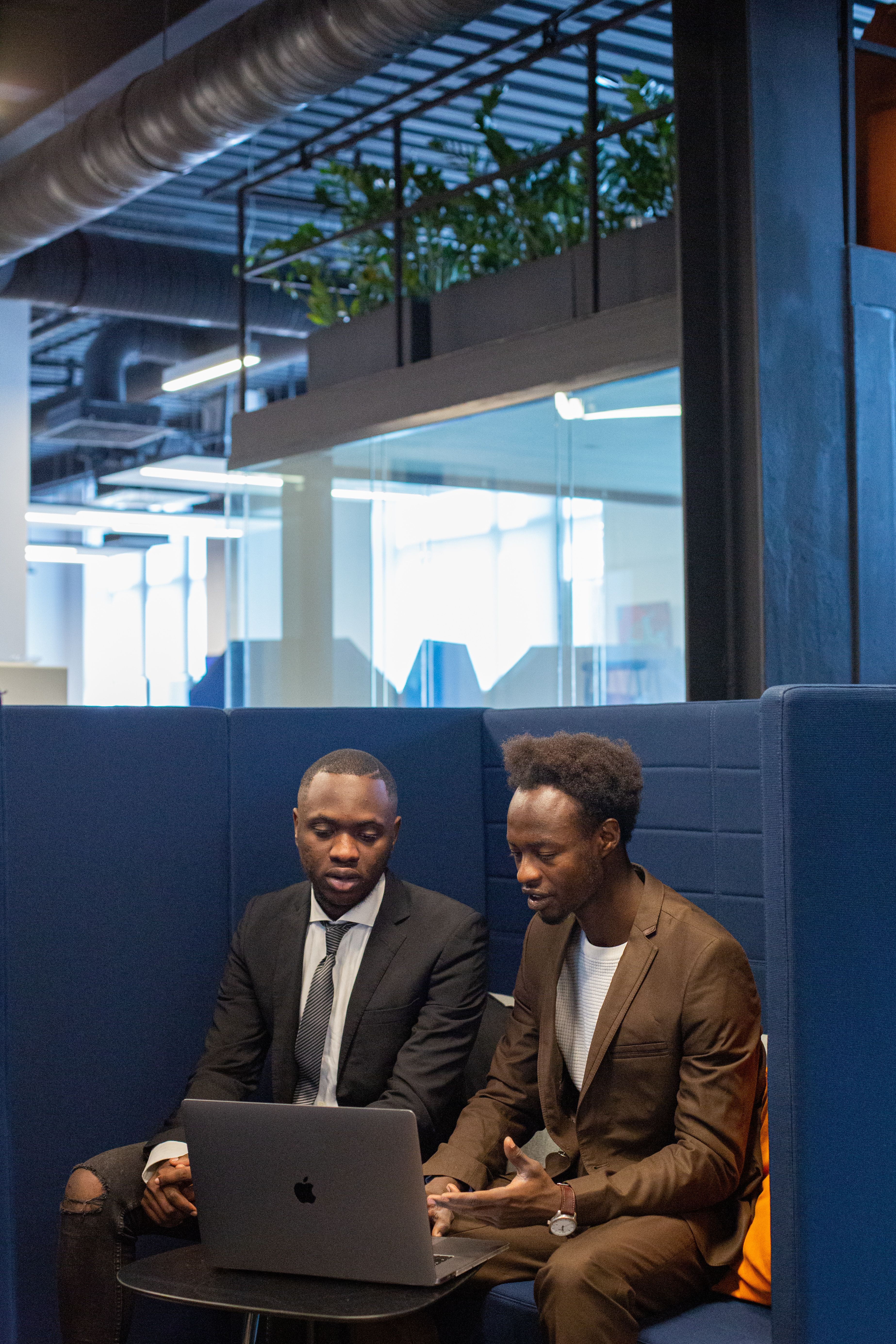 Two men engaged in a business discussion at a laptop in a modern office.