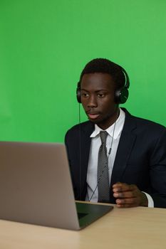 Business professional in formal attire engaged in video call against green screen backdrop.