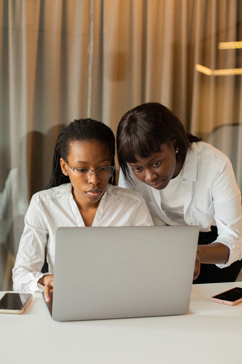 Two women in business attire working together on a laptop