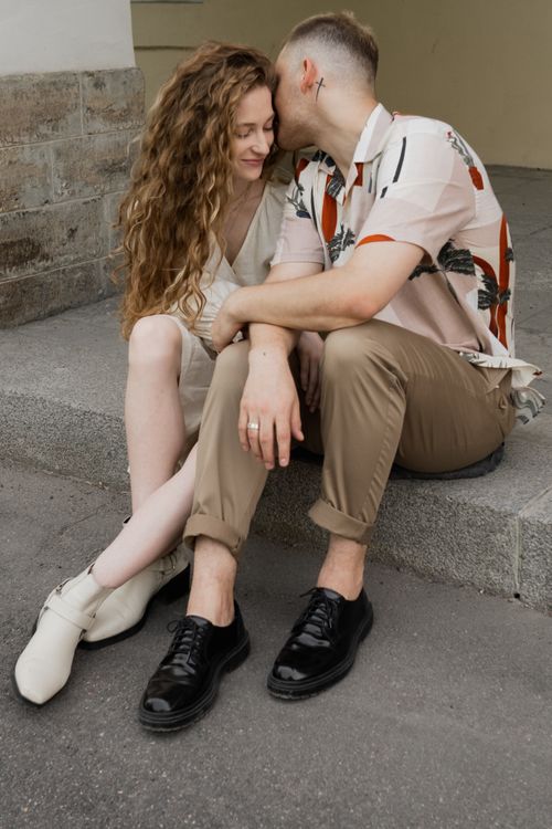 Free A young couple sitting closely on outdoor steps, sharing a tender moment with affection. Stock Photo