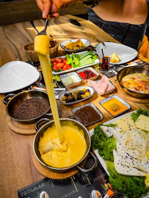 Free A vibrant Turkish breakfast with cheeses, dips, vegetables, and a cheesy dish on a wooden table. Stock Photo