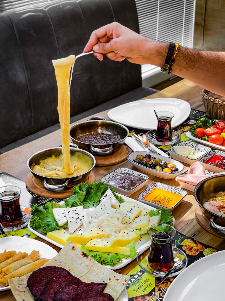 A Person Getting Melted Cheese From A Pan