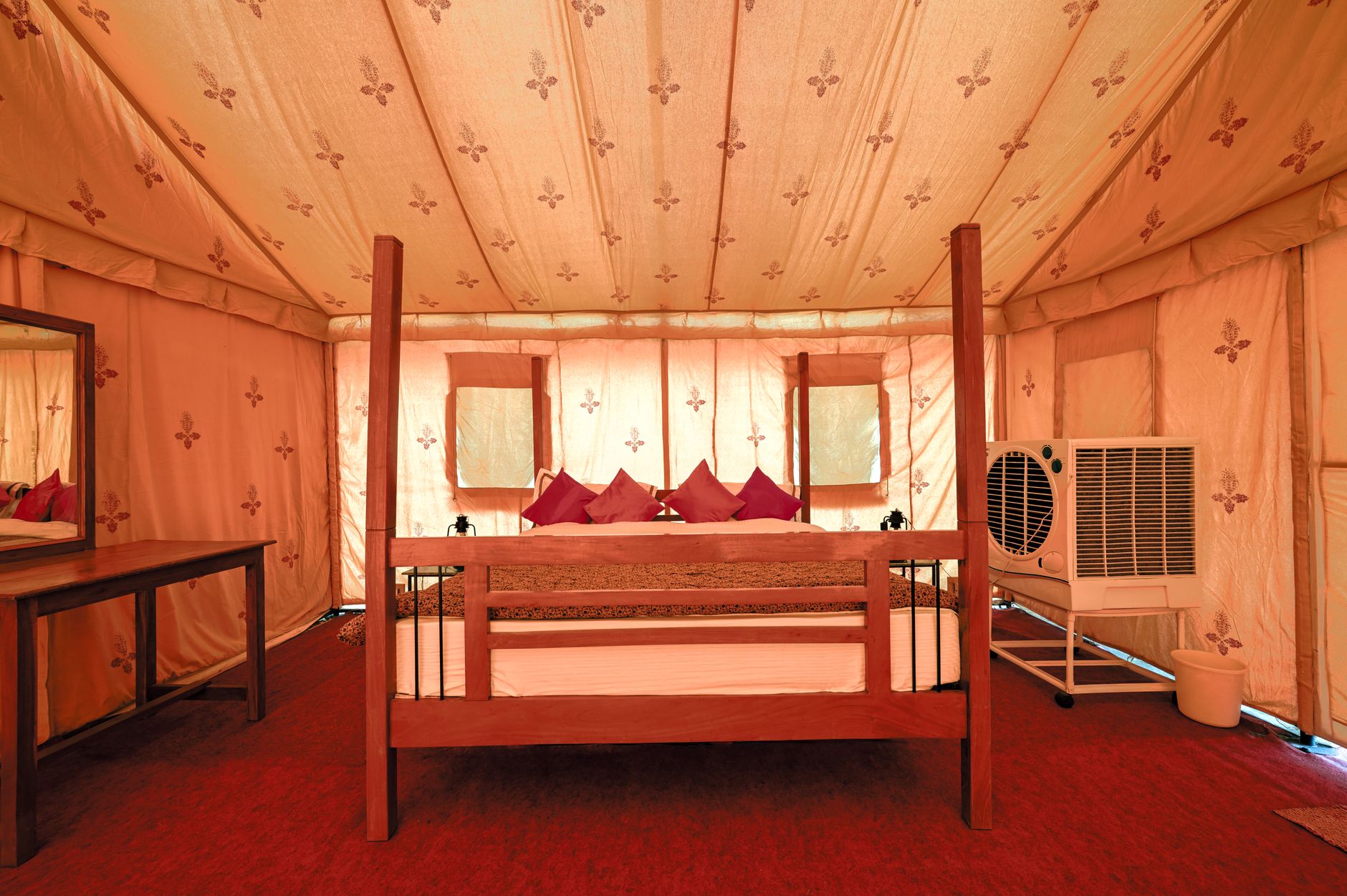 Cozy glamping tent with a wooden bed and air cooler in Jaisalmer, India