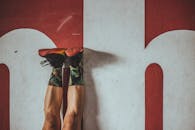 穿着五颜六色的袜子和运动鞋的人正在大胆的红色墙壁前锻炼