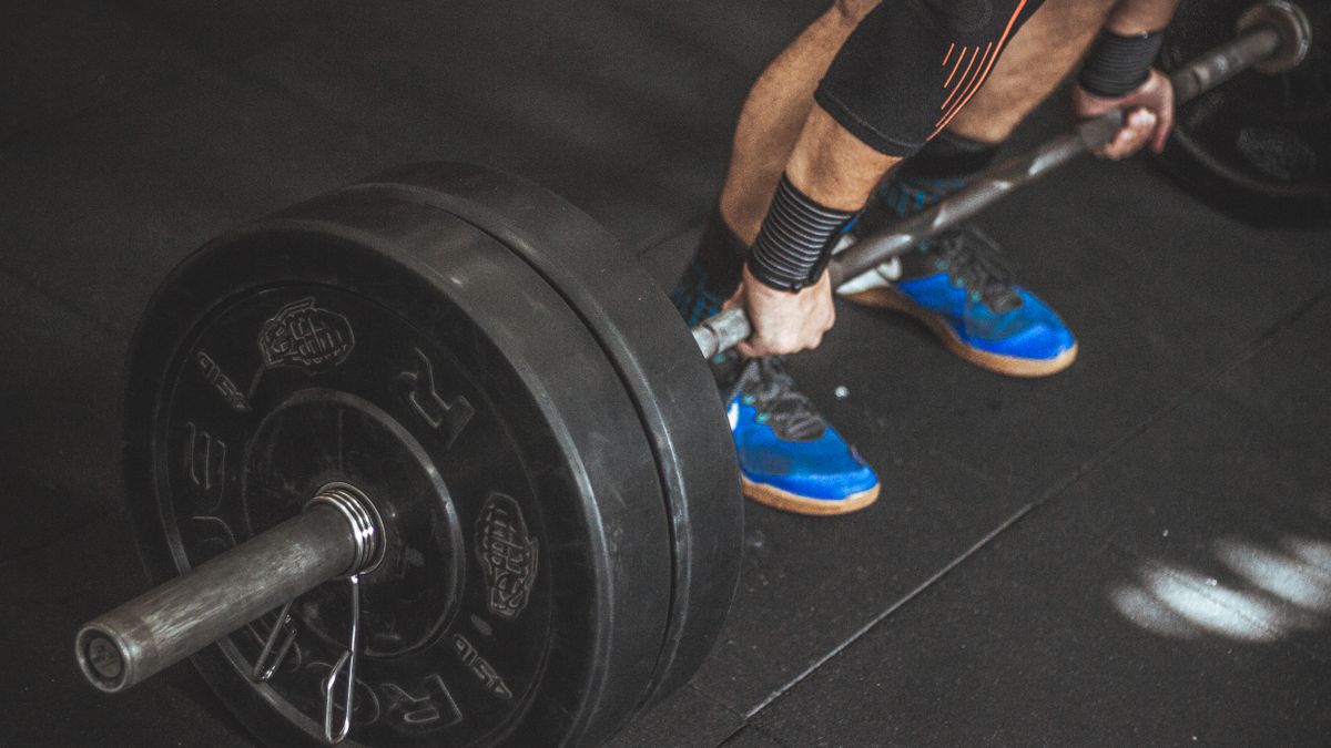 A man performing a deadlift with a heavy barbell in a gym setting, showcasing strength and fitness.