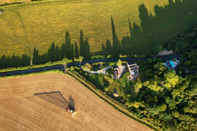 Aerial view of UK countryside featuring farmland and dwellings representing a mixed landlord estate with agricultural and residential property