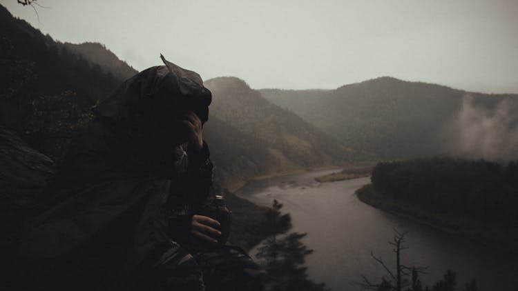 Tired Tourist In Raincoat Resting On Mountain Trip