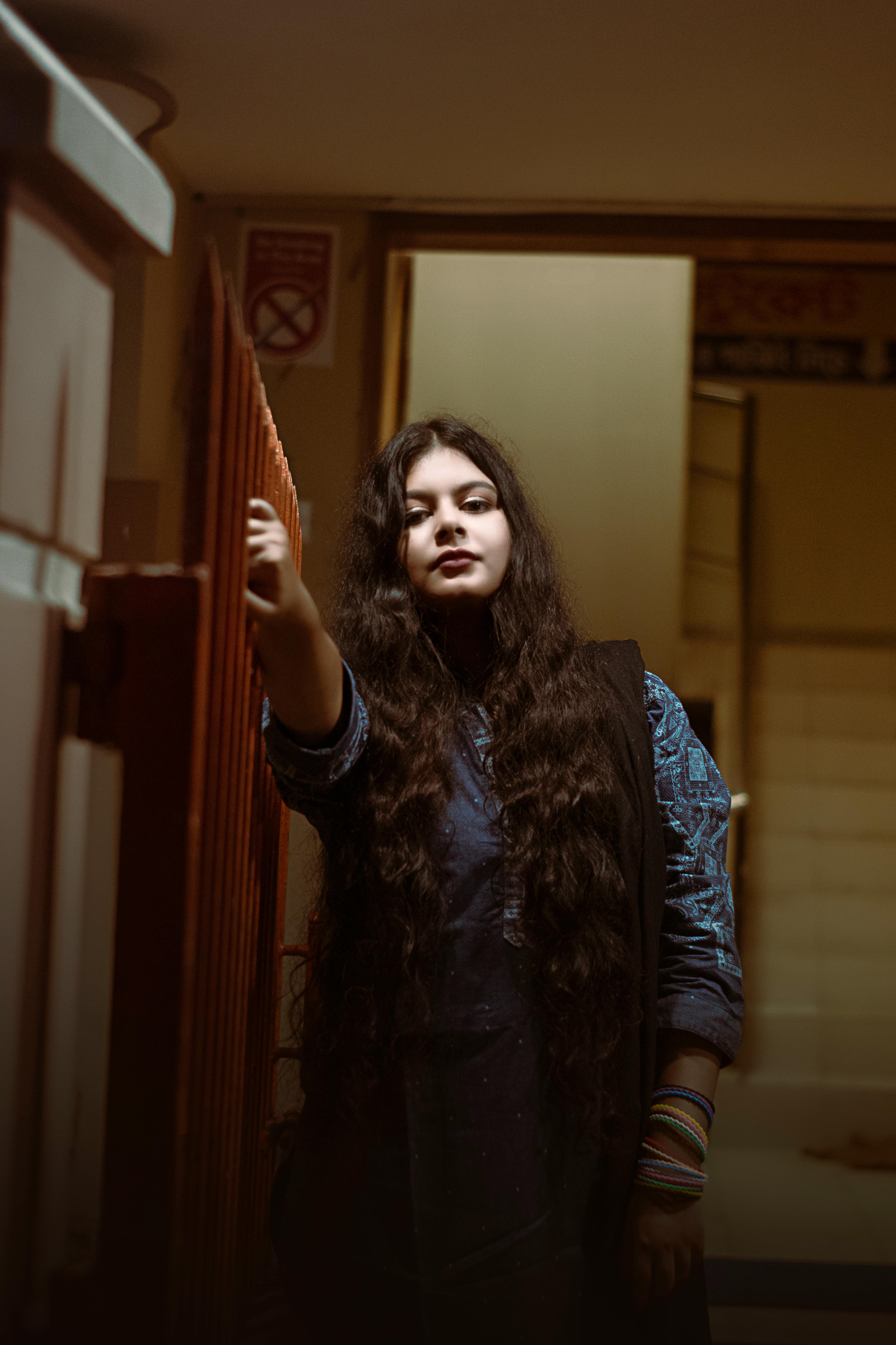 A striking portrait of a woman with long hair in an indoor setting, showcasing mood and expression.