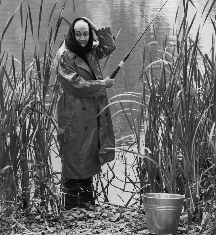 A Grayscale Of A Woman Fishing On A Lake