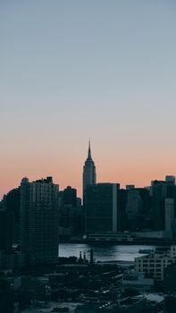 Dramatic view of NYC skyline featuring the iconic Empire State Building at sunset.