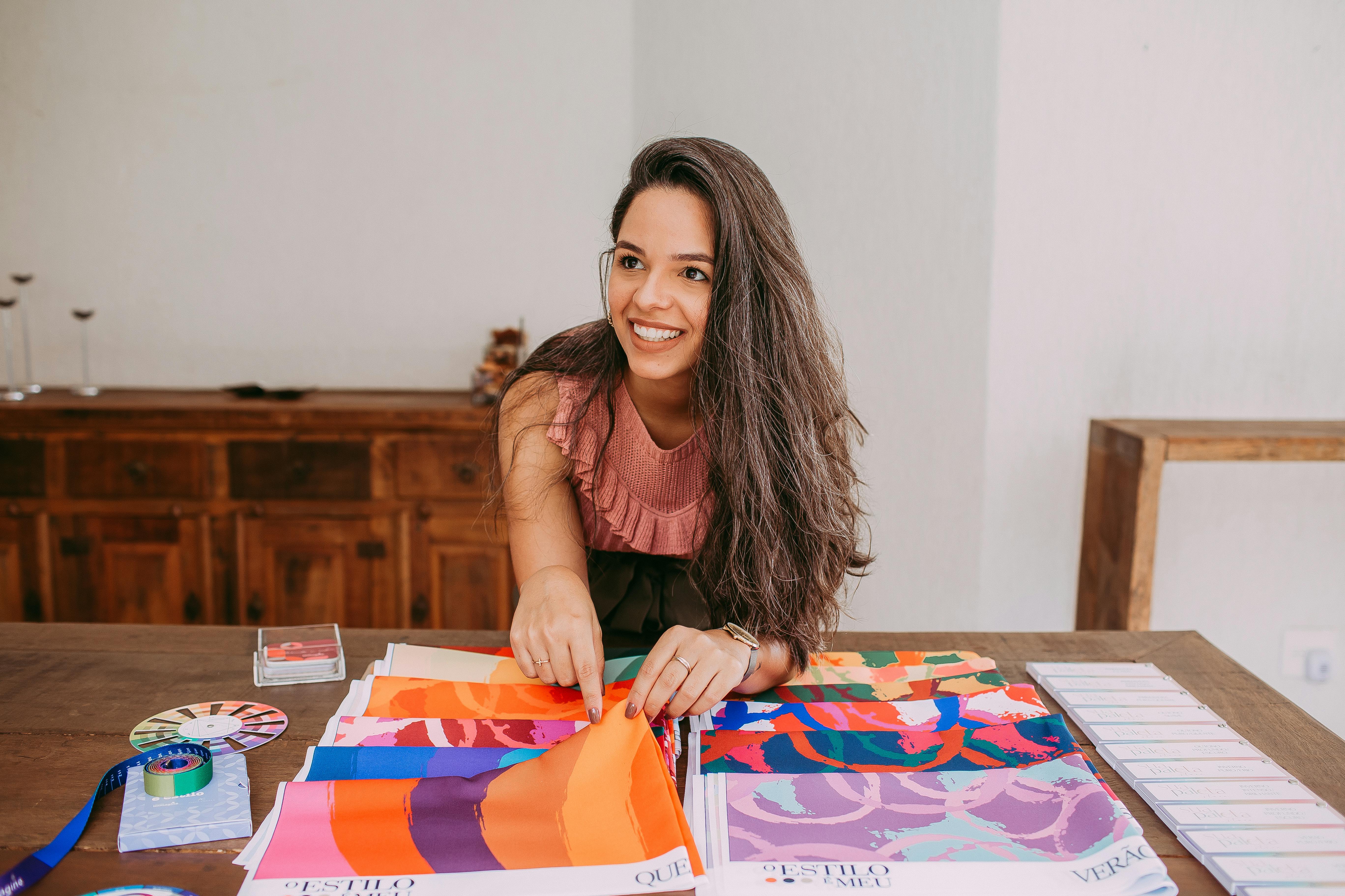 Smiling woman examining colorful fabric samples at a table indoors.