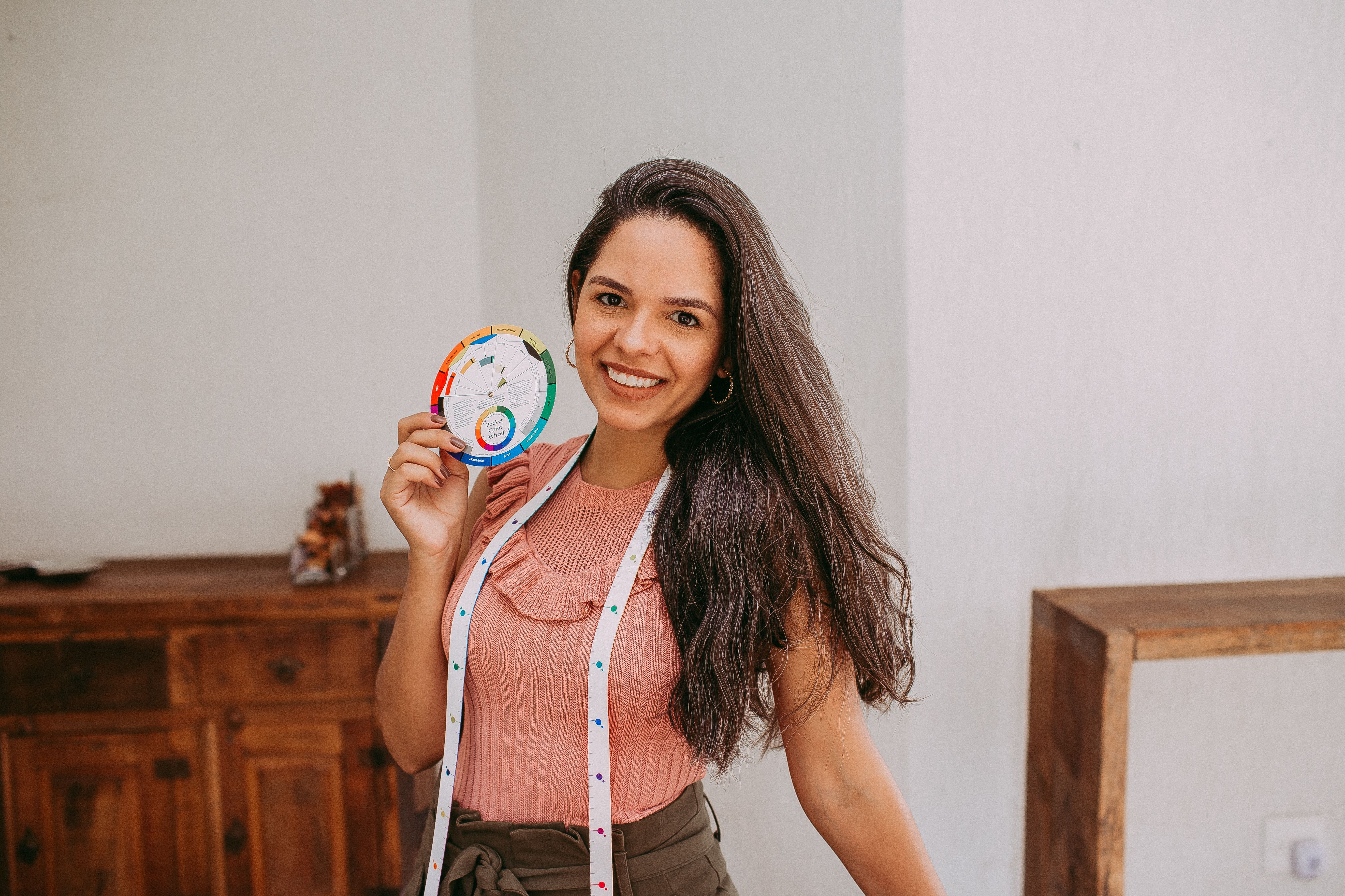 Smiling woman holding a colorful wheel indoors with natural lighting and bright ambiance.