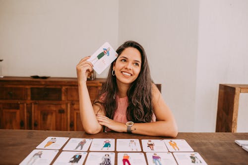 Brunette Woman Sitting behind Table with Fashion Cards