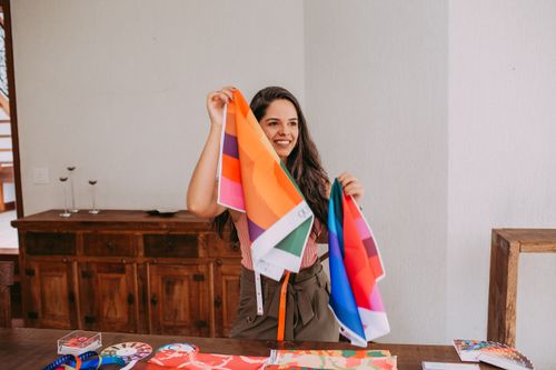 Free A cheerful woman holds vibrant fabric swatches inside a stylish room, offering design inspiration. Stock Photo