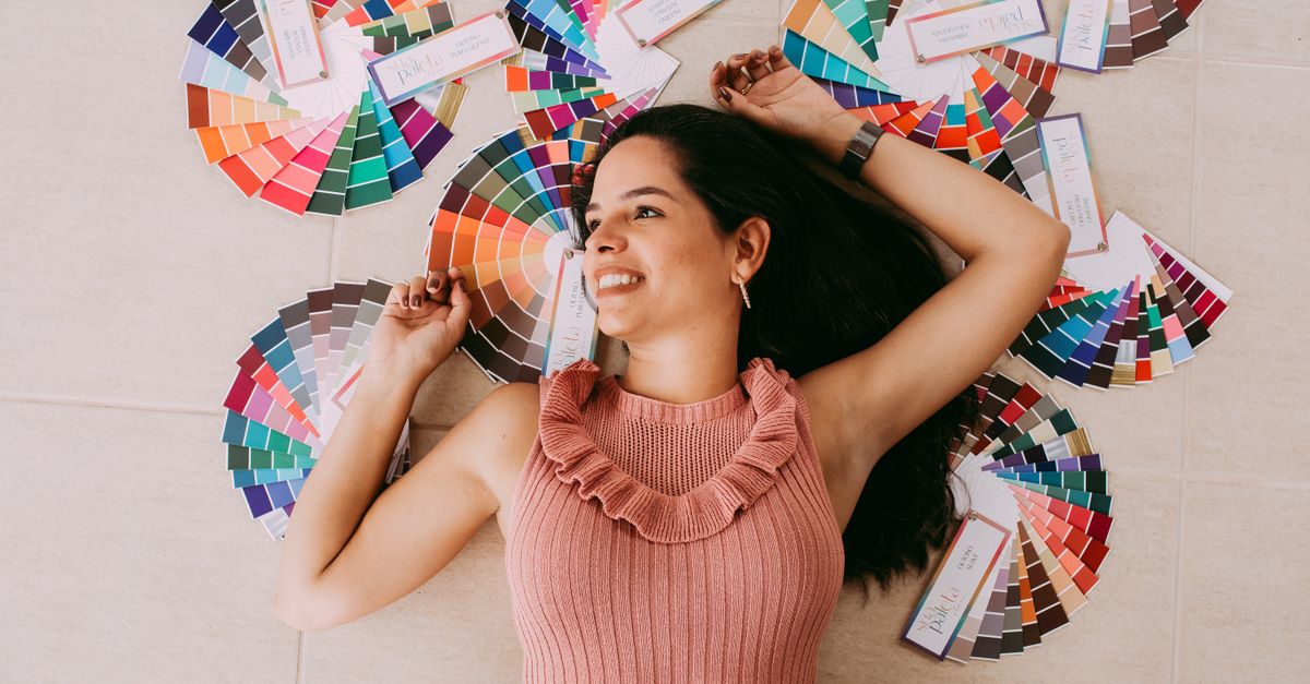 Happy woman lying surrounded by colorful palettes, showcasing vibrant design inspiration.